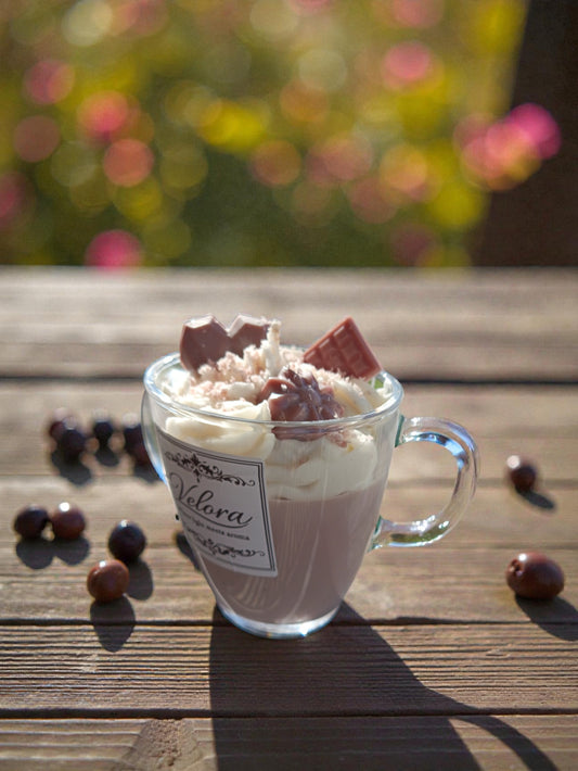 Χειροποίητο κερί σόγιας εμπνευσμένο από την απόλυτη gourmand εμπειρία ζεστής σοκολάτας, σχεδιασμένο ως ένα μοναδικό dessert candle που ξεχωρίζει. Τοποθετημένο σε κομψή κούπα, διαθέτει πλούσια βάση που θυμίζει λιωμένη σοκολάτα και κορυφή με χειροποίητη «σαντιγί» κεριού, σοκολατένιες καρδιές και τρίμματα σοκολάτα